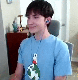a young man wearing headphones and a blue shirt with a bunny on it is sitting in a chair .