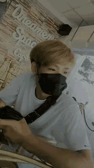 a man wearing a black mask is sitting in front of a sign that says dreamer 's spoon cafe