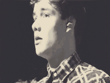 a close up of a man 's face in a black and white photo . he is wearing a plaid shirt .