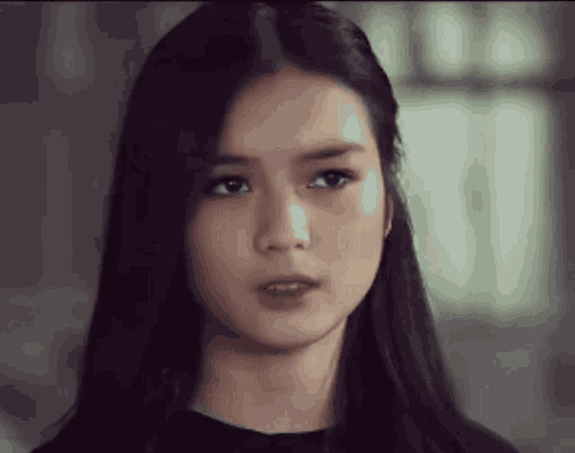 a woman with long black hair is looking at the camera