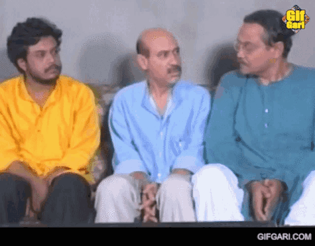 three men are sitting next to each other on a couch with gifgari.com at the bottom
