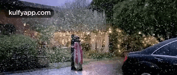 a man and a woman are standing in front of a car in the rain .