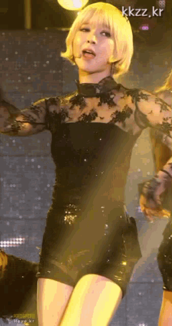 a woman in a black dress is dancing on a stage with kkzz.kr written in the corner