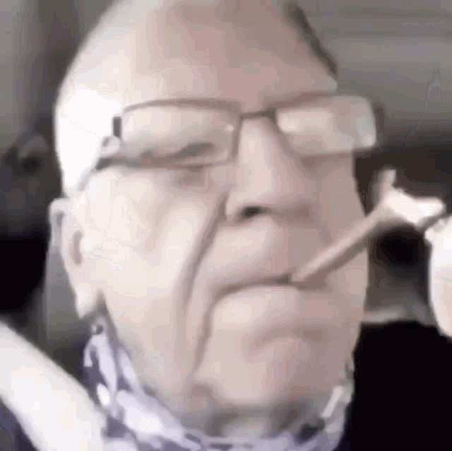 an elderly man wearing glasses is smoking a cigarette .