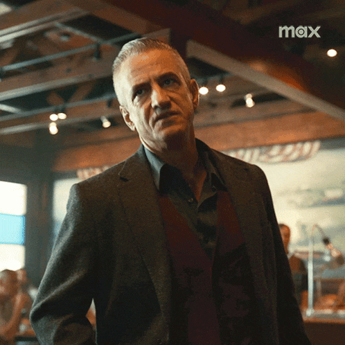 a man in a suit is standing in a room with the word max on the bottom