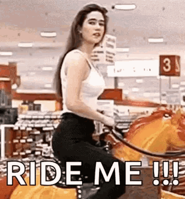 a woman is riding a merry go round in a store with the words `` ride me !!! '' written on it .