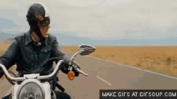a man is riding a motorcycle down a road with a make gifs at gifsoup.com logo