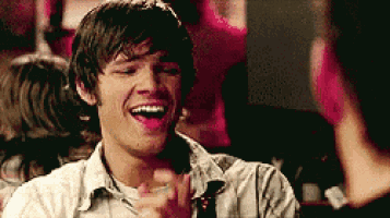 a man is laughing and clapping his hands in a bar