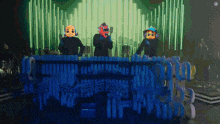 a group of people wearing masks are playing instruments on a stage in front of a crowd .
