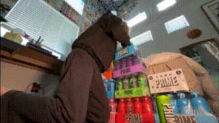a person standing in front of a stack of cans of prime