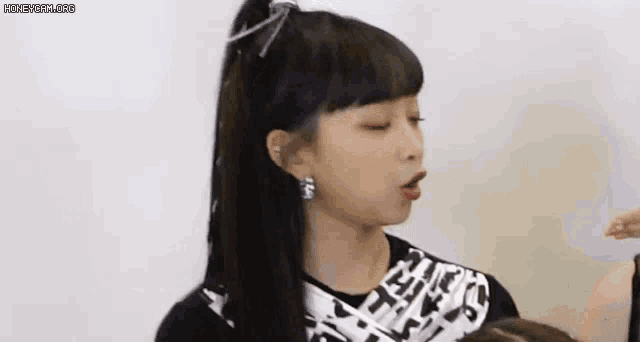 a young girl with a ponytail and earrings is making a face .