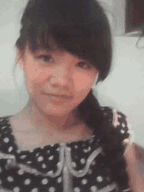 a young girl in a polka dot dress is taking a selfie with her phone .