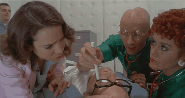 a man with glasses is being examined by a doctor and two nurses