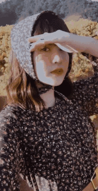a woman wearing a floral dress and a headband covering her eyes
