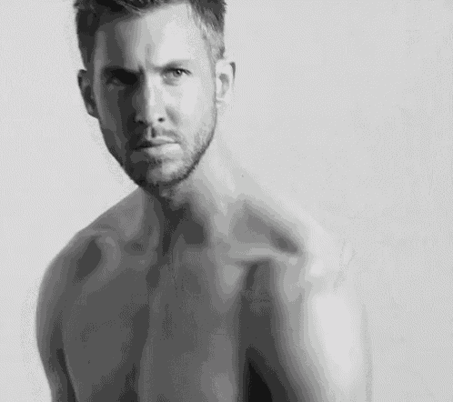 a shirtless man with a tattoo on his arm is sitting down with his legs crossed