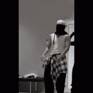 a man wearing a bandana and a plaid shirt stands in a room