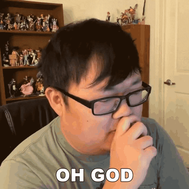 a man wearing glasses and a shirt that says oh god covering his nose