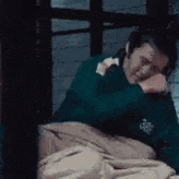 a man is laying in bed with his head on his hand .
