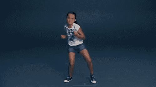 a young girl wearing a white shirt and shorts is dancing