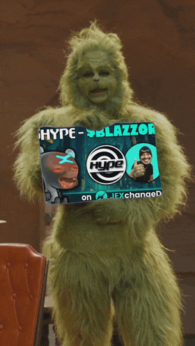 a grinch is holding a sign that says hype-blazzor on it
