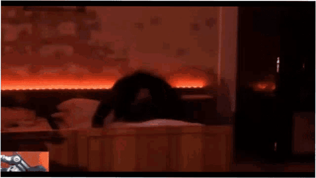 a man is sitting on a bed in a dark room with red lights on the wall .