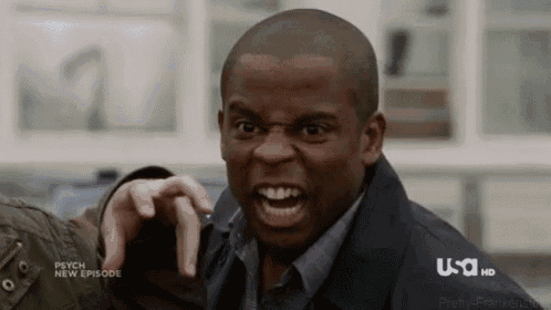a man is making a funny face while pointing at the camera .