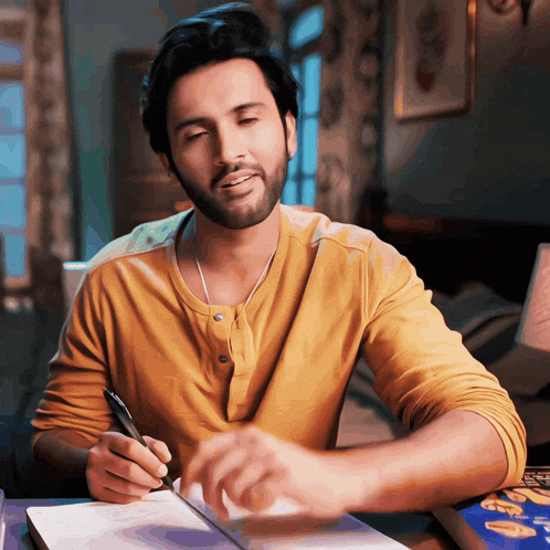 a man in a yellow shirt is writing on a notebook