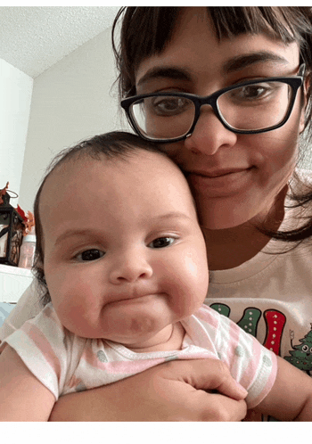 a woman with glasses is holding a baby in her arms
