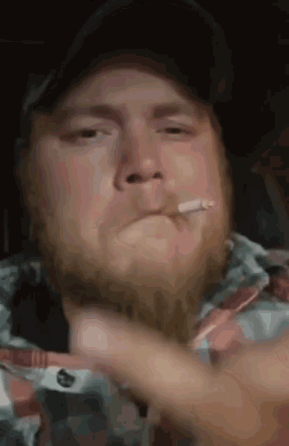 a man in a plaid shirt is smoking a cigarette and giving the middle finger