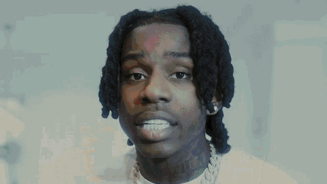 a close up of a young man with dreadlocks