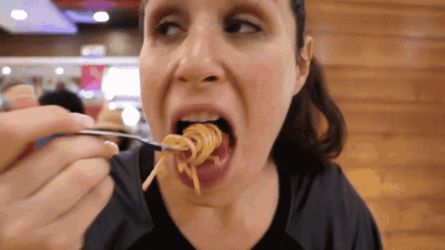 a woman eats spaghetti with a fork in her mouth