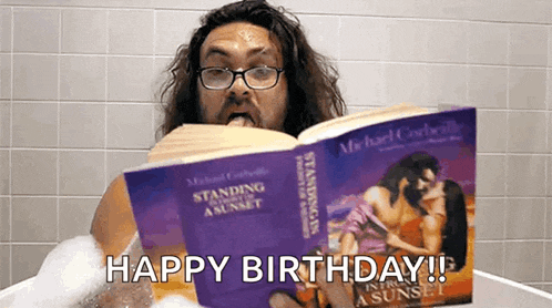 a man is sitting in a bathtub reading a book and says happy birthday .