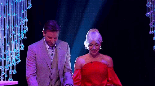 a man in a suit and a woman in a red dress are on a stage .