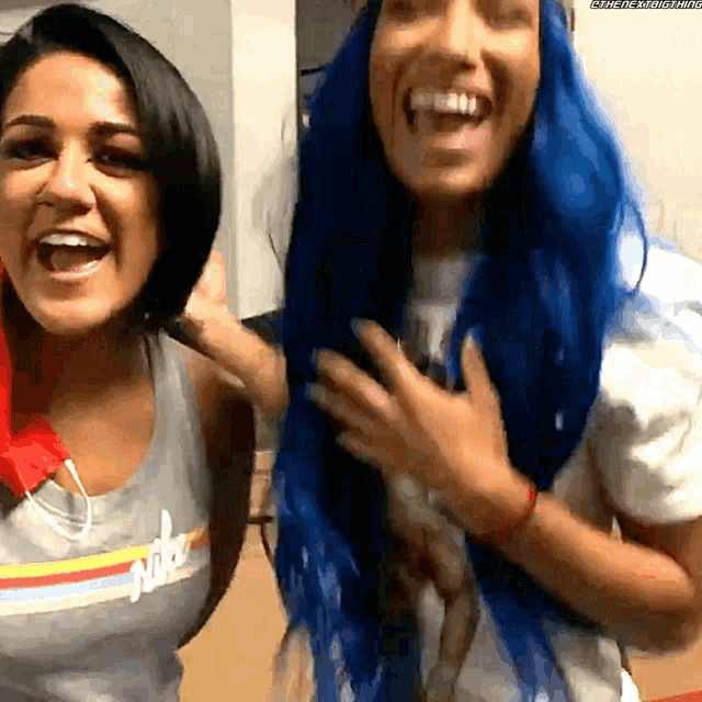two women with blue hair are laughing and one has the word nike on her shirt