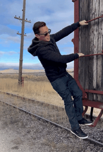 a man wearing sunglasses is pulling a wooden wall