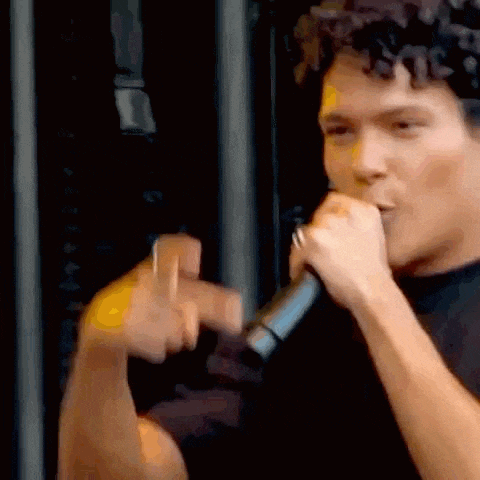 a man is singing into a microphone and making a peace sign with his hands .