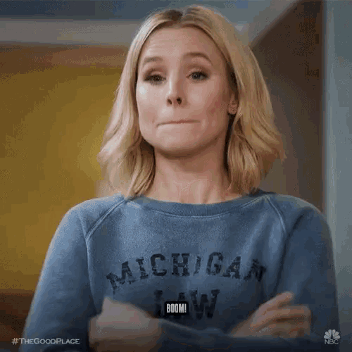 a woman in a blue sweater is making a funny face and says boom .