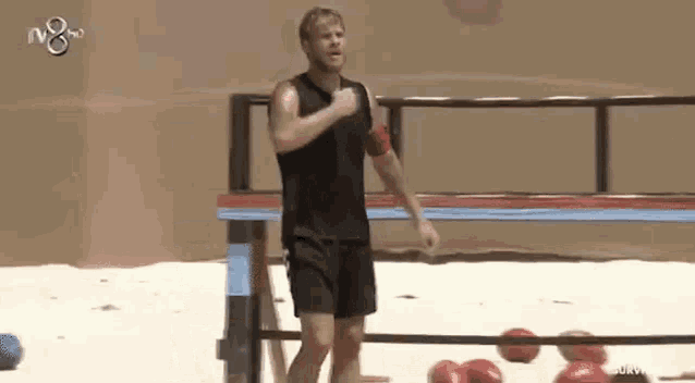 a man in a black tank top and shorts is running on a beach .