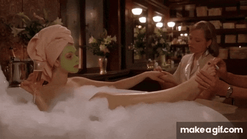 a woman in a bathtub with a green face mask on