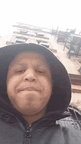 a man wearing a hooded jacket is making a funny face