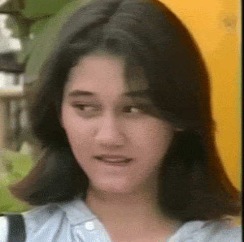 a close up of a woman 's face with long black hair and a blue shirt .