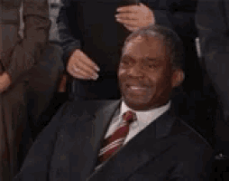 a man in a suit and tie is sitting in front of a group of people and saying that 's a penis .