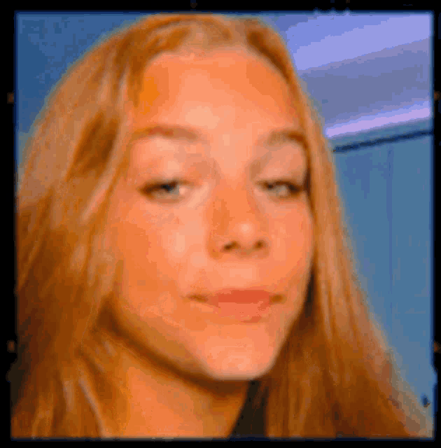a close up of a woman 's face with long hair and a blue background .