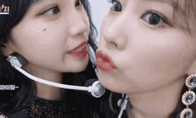 two girls are kissing each other and one has a microphone around her neck