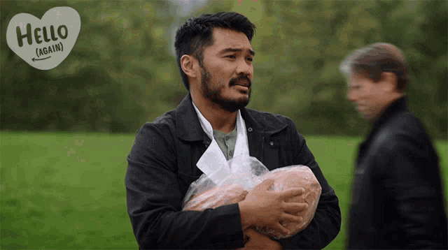 a man holding a loaf of bread with a heart that says hello again on it