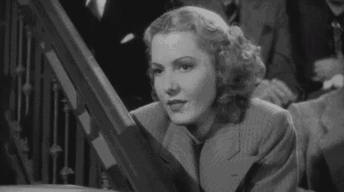 a black and white photo of a woman in a suit and tie sitting on a staircase .