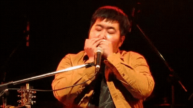 a man singing into a microphone while covering his mouth with his hands