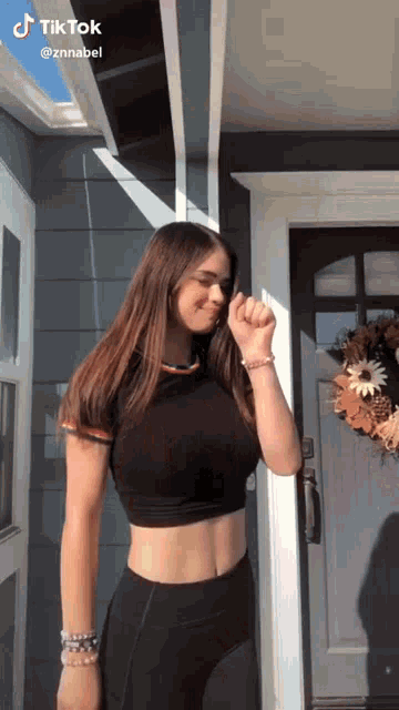 a woman in a black crop top and black leggings is standing in front of a door .