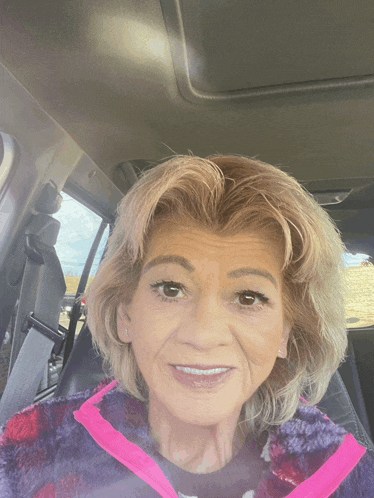 a woman in a purple and pink sweater smiles for the camera