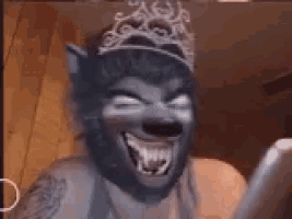 a woman wearing a wolf mask and a tiara is laughing .